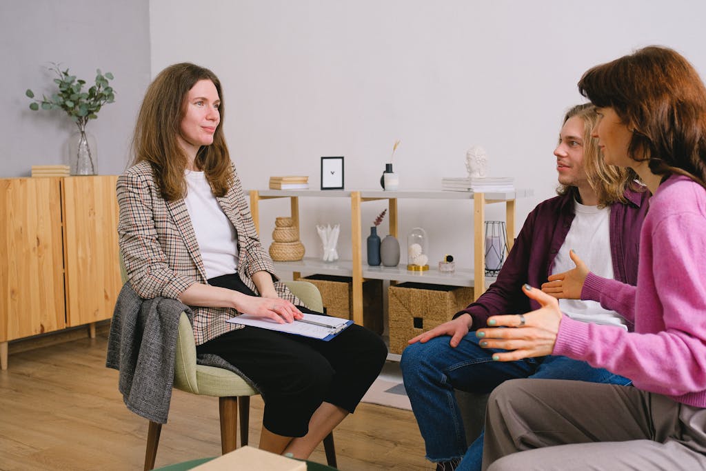 Young adults discuss with a counselor during an indoor therapy session.